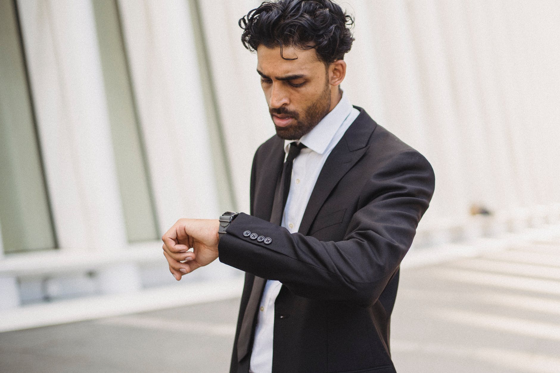 a bearded man in a corporate attire looking at his watch