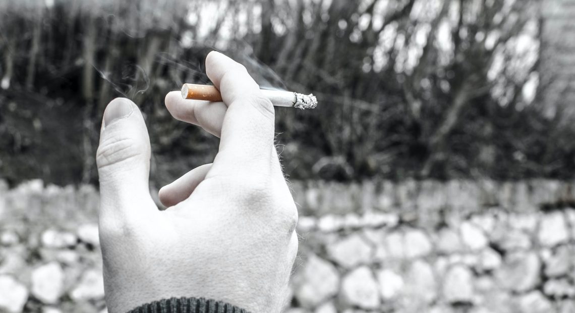 selective color photography of person holding cigarette stick